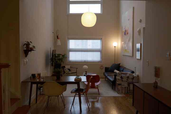 A white and brown toned combined living and dining room featuring a modern sofa, armchair, and pendant light with a natural ambiance