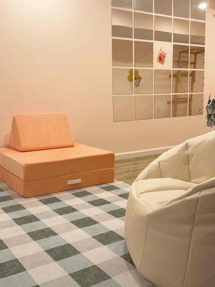 Warm beige and white toned kids' room featuring a cozy bean bag and play couch with a soft atmosphere