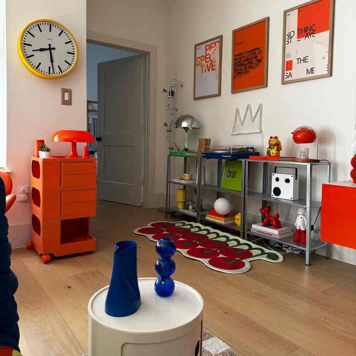 A trendy living room with red and yellow hues and wood tones, featuring various objets and wall decor for a colorful aesthetic