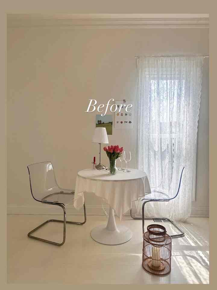 White-toned dining room featuring transparent chairs and round table with flowers and lamp in a simple setting