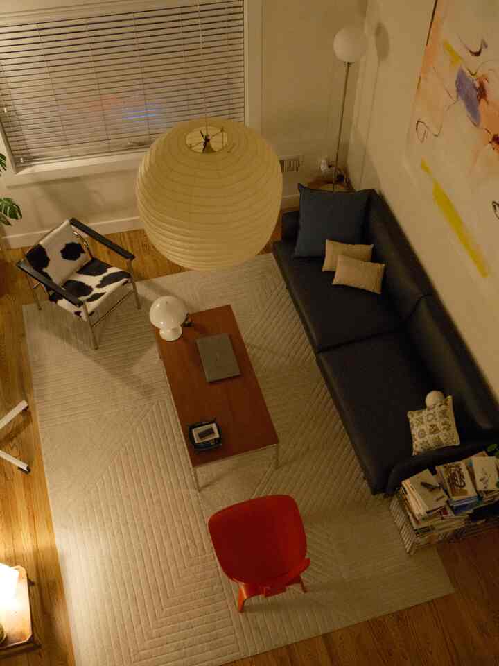 Cozy living room featuring beige rug, black sofa, armchair, and wooden coffee table in warm natural tones
