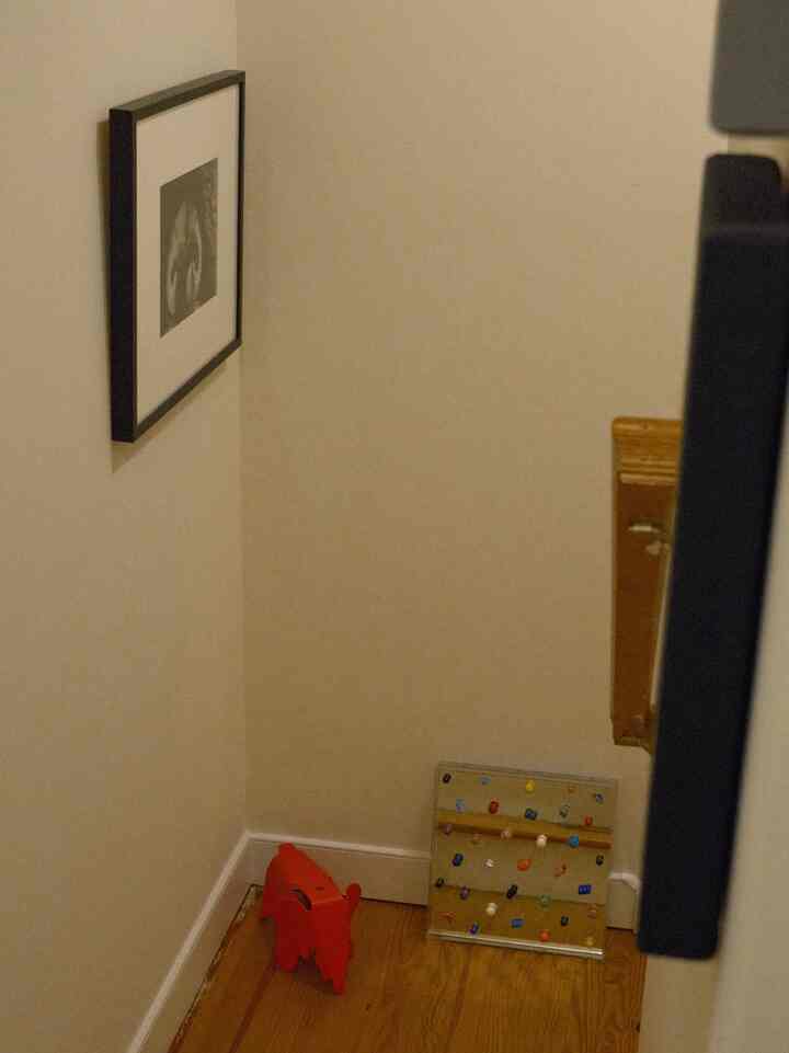 Minimal corner space with white walls and light wood flooring featuring a red objet and decorative items