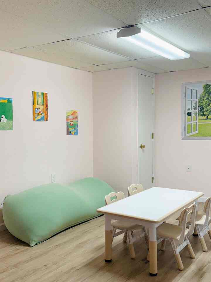 White and mint toned kids' room with child-sized table, chairs, and bean bag creating a cozy atmosphere