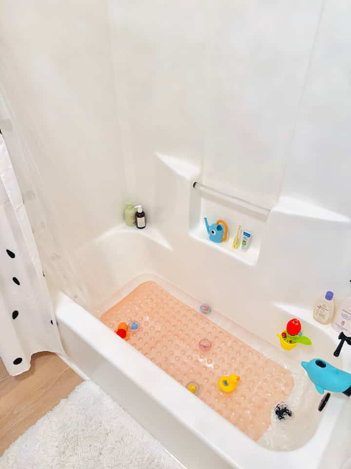 White-toned bathroom featuring baby bath toys and a bath mat in a clean and cozy setting