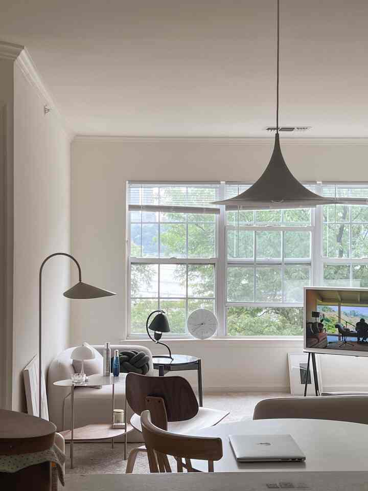 Beige and wood-toned living room with large windows and cozy lighting, creating a summer atmosphere