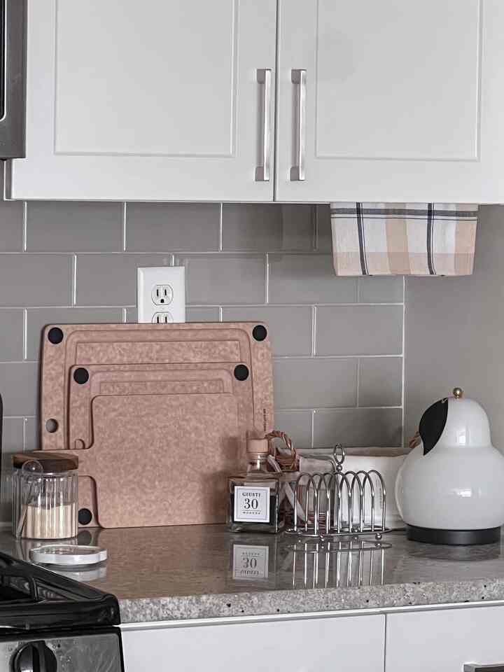 White and beige toned kitchen featuring cutting boards and kitchen towel with tidy arrangement