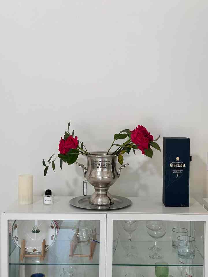 Minimalistic white-toned home bar featuring a silver vase with red roses as focal points
