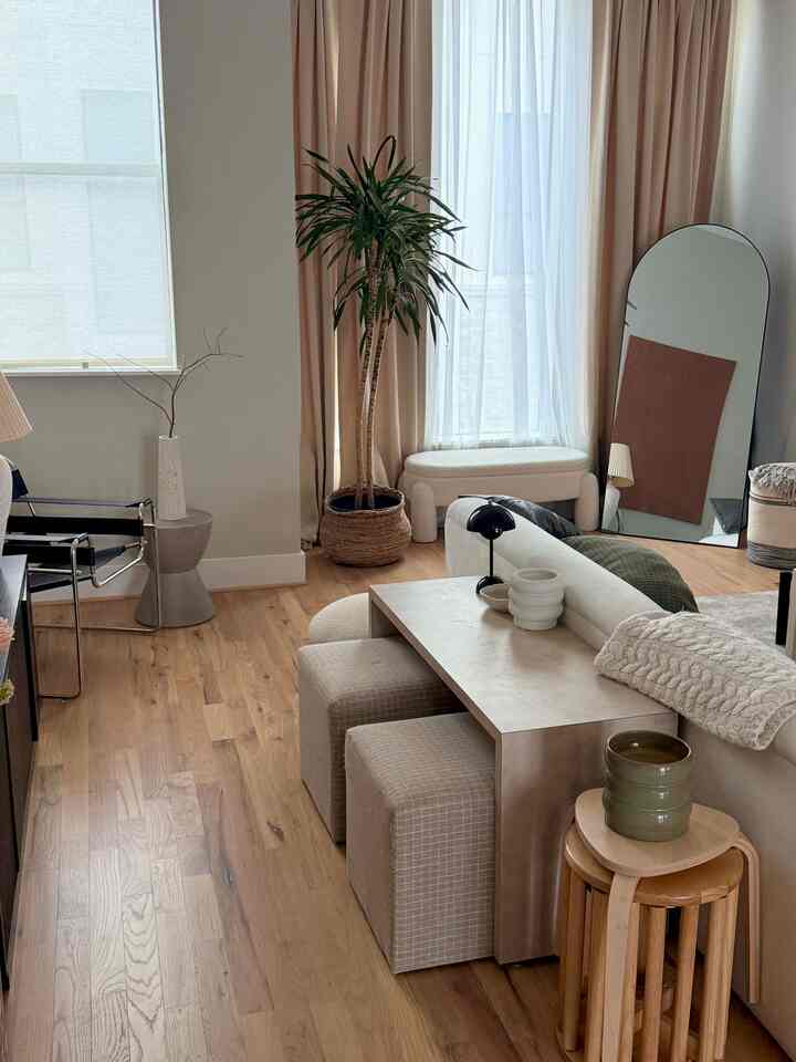 Natural wood tones and white curtains define a modern Japandi-style living room with a large plant as a focal point