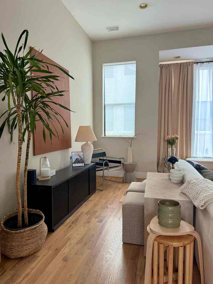 Natural wood tone living room featuring plants, modern armchair and stools in a Scandinavian style space
