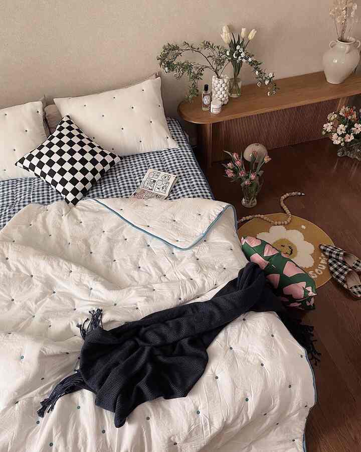 A cozy bedroom in white and blue tones featuring patterned cushions and natural wood furniture