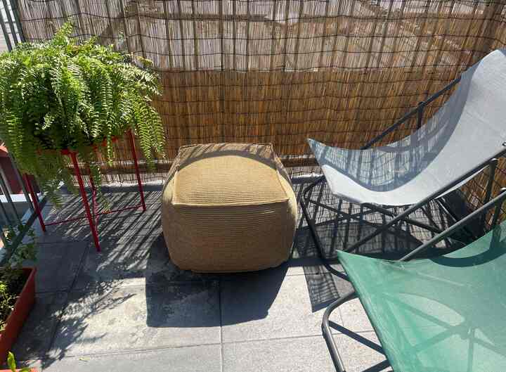 Warm beige and natural-toned balcony space featuring outdoor chairs and knitted bean bag, providing a cozy outdoor relaxation area