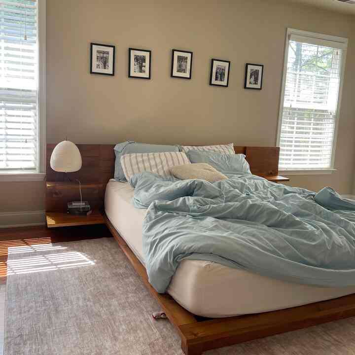 Bright and natural bedroom with beige walls, wood tone bed frame, and light sky blue bedding