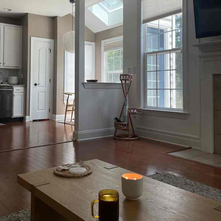 Beige and white toned living room and kitchen featuring wooden furniture and natural light, creating a cozy atmosphere