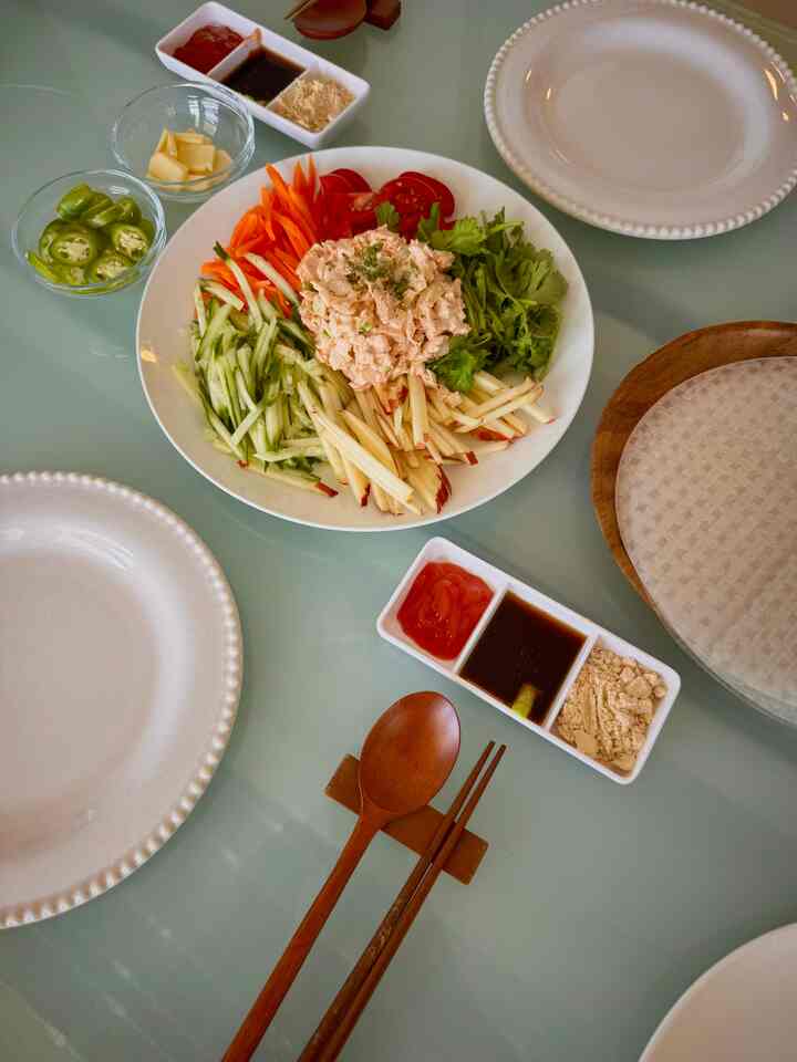 Light-toned kitchen table featuring white plates and fresh vegetable salad on a transparent glass surface