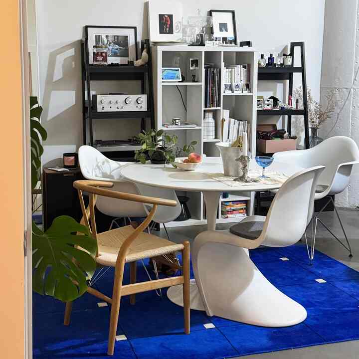White and blue toned living and dining space featuring a round dining table and diverse chairs with cozy atmosphere