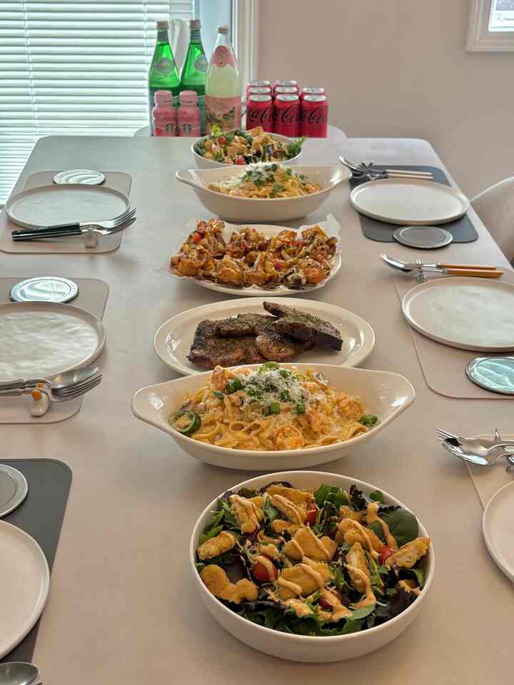 White-toned dining room featuring a table set with various plates, bowls, food, and beverages creating a cozy home party atmosphere