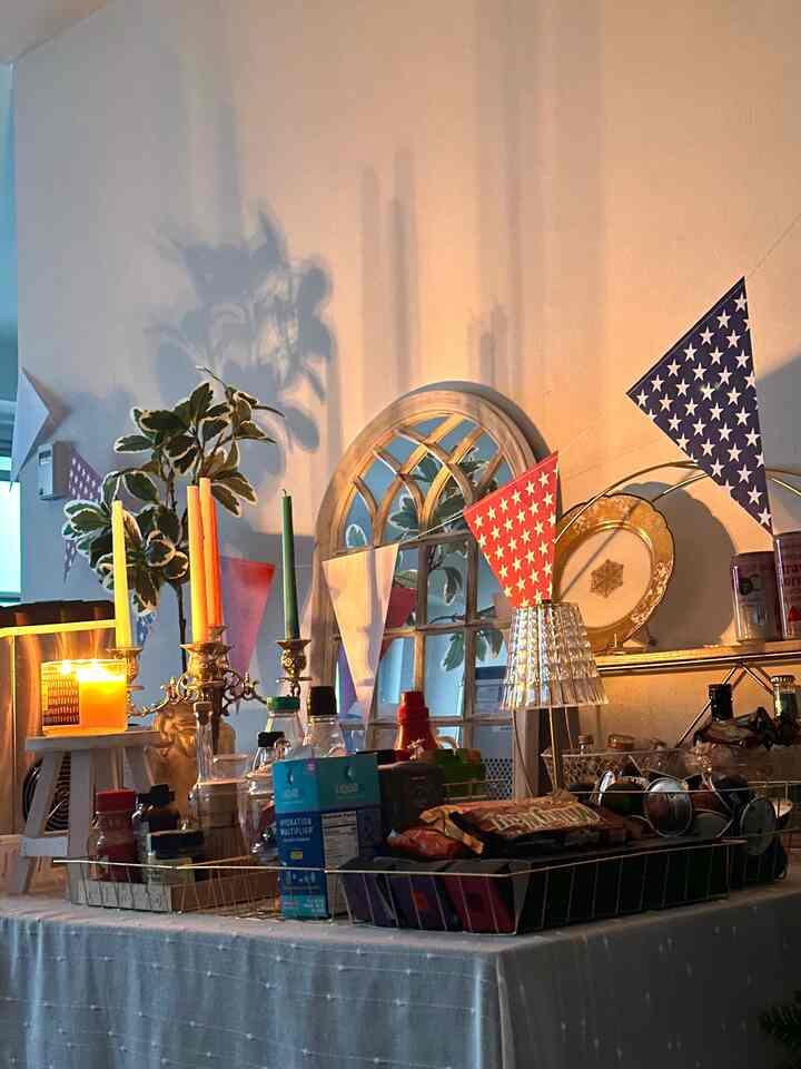 Cozy space featuring a white wall with red and blue pennant garland, a dining table set for party with candles lit