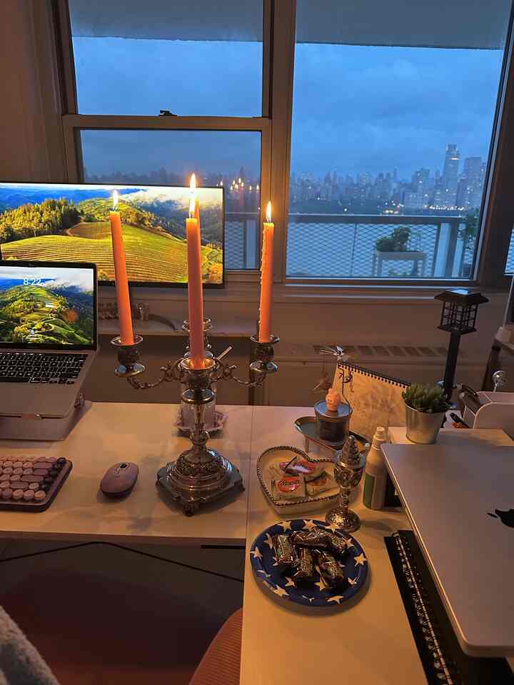 Warm yellow candlelight and silver accents in a home office space with a cozy atmosphere showcasing a city night view outside the window