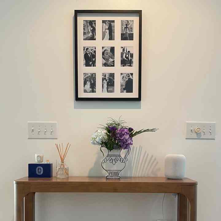 Simple modern interior with white walls and wood tone console table featuring candle, diffuser, vase and HomePod speaker