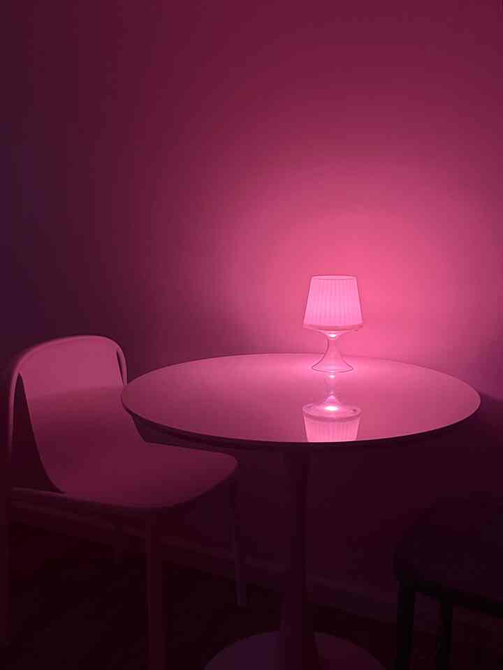 Pink-lit modern dining room featuring a round table and chairs in a simple setting