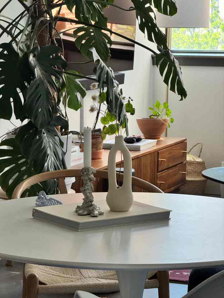 Natural color and wood tone dining room featuring a white dining table with candles and vases, creating a cozy atmosphere