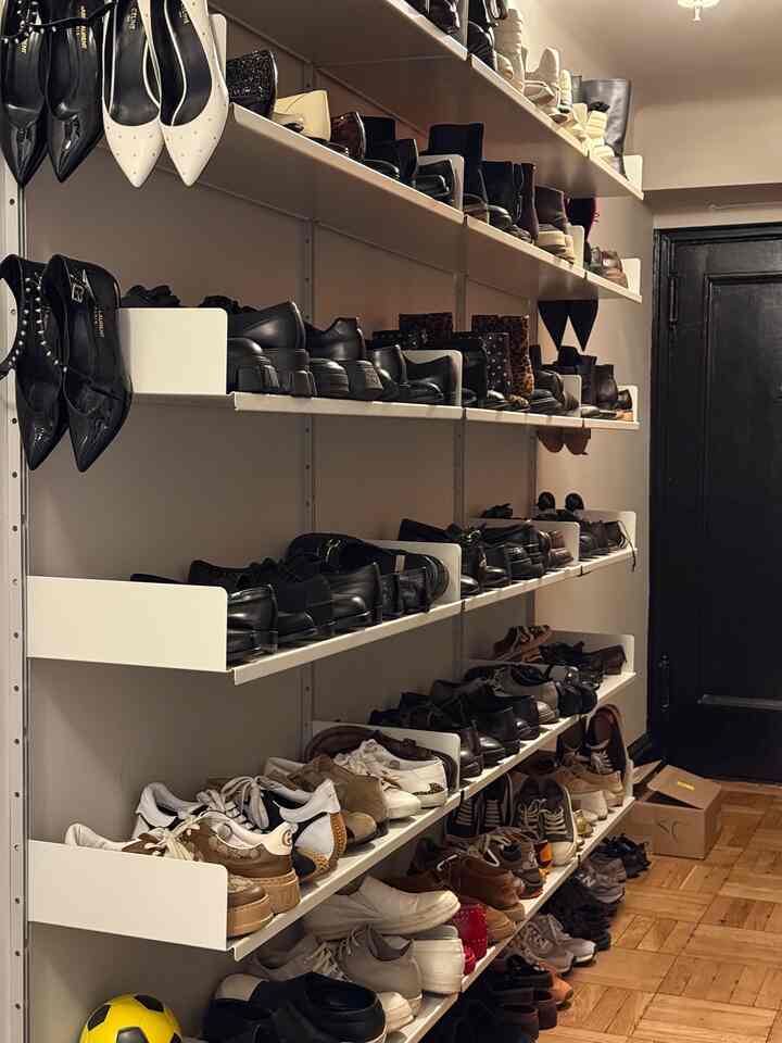 Narrow shoe storage space featuring white shelves organized with various shoes