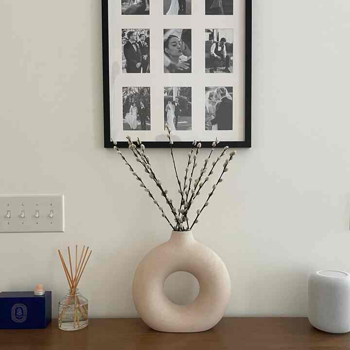A simple living room console with a beige circular ceramic vase and calm decor arranged in a serene interior