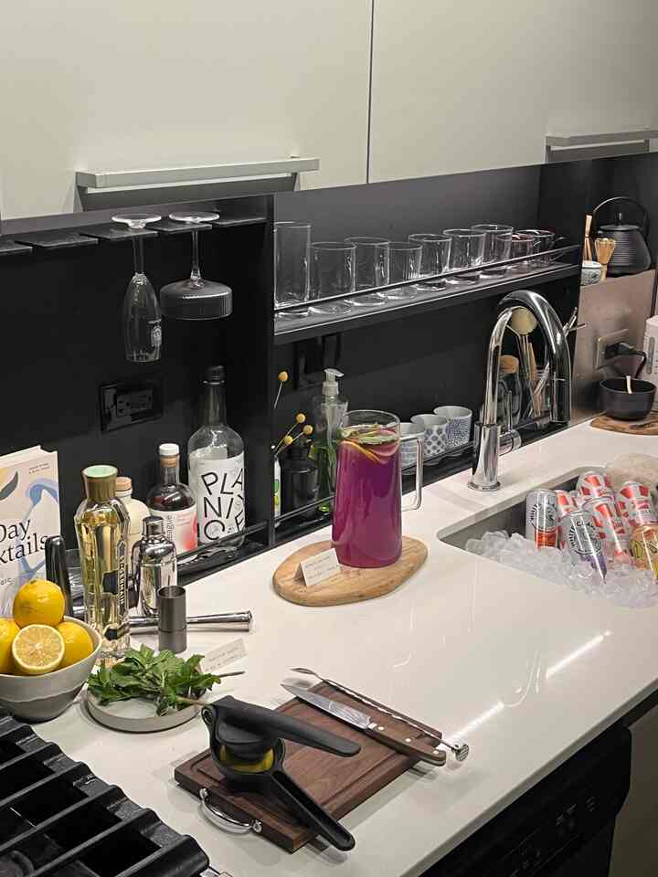 A modern kitchen space in white and black tones featuring a sink turned into an ice-filled beverage tub for a home bar setup