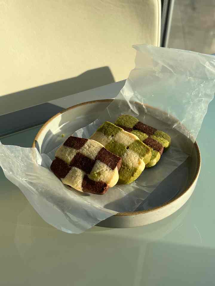 Natural modern home cafe setup with beige Hasami porcelain plate and checkered cookies on gray modern dining table under warm daylight