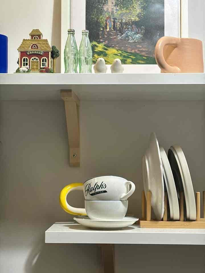 White and yellow toned kitchen shelf featuring Ralph's coffee cups and plates in a cozy setting