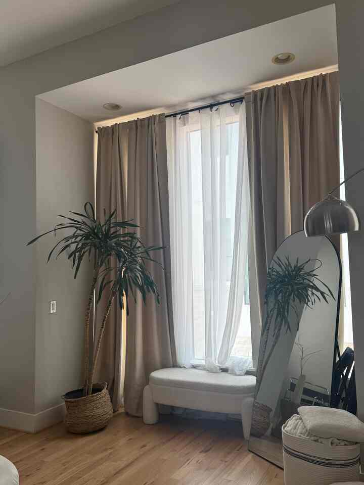 Beige and wood tone balcony space featuring an arched full length mirror and a plant in a natural modern style interior