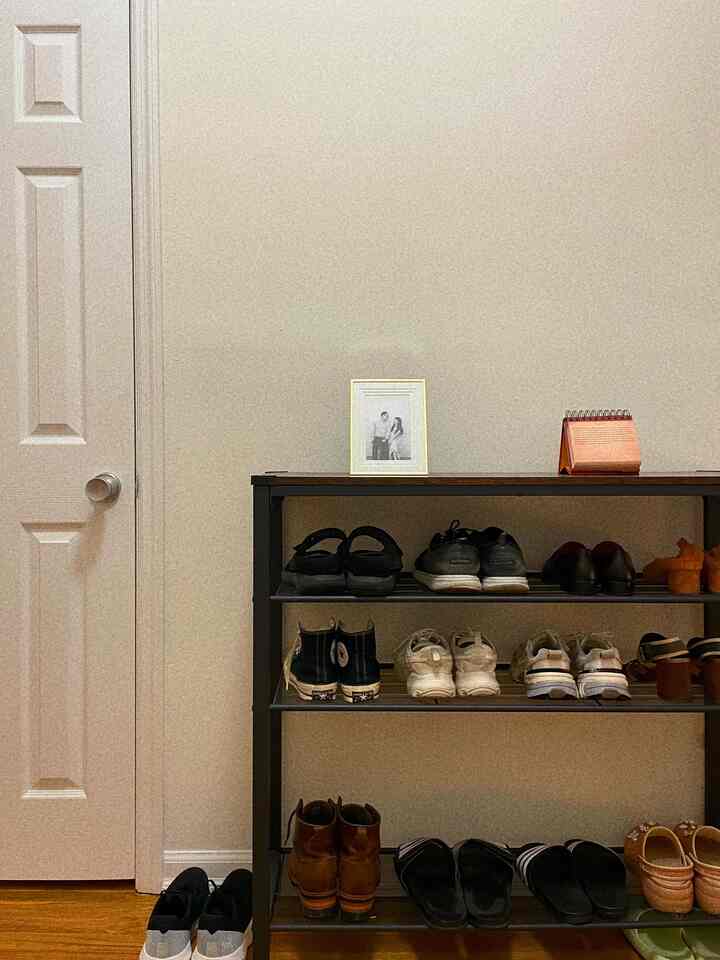 Ivory and brown toned entrance featuring a gold picture frame and organized shoe rack with a calm atmosphere