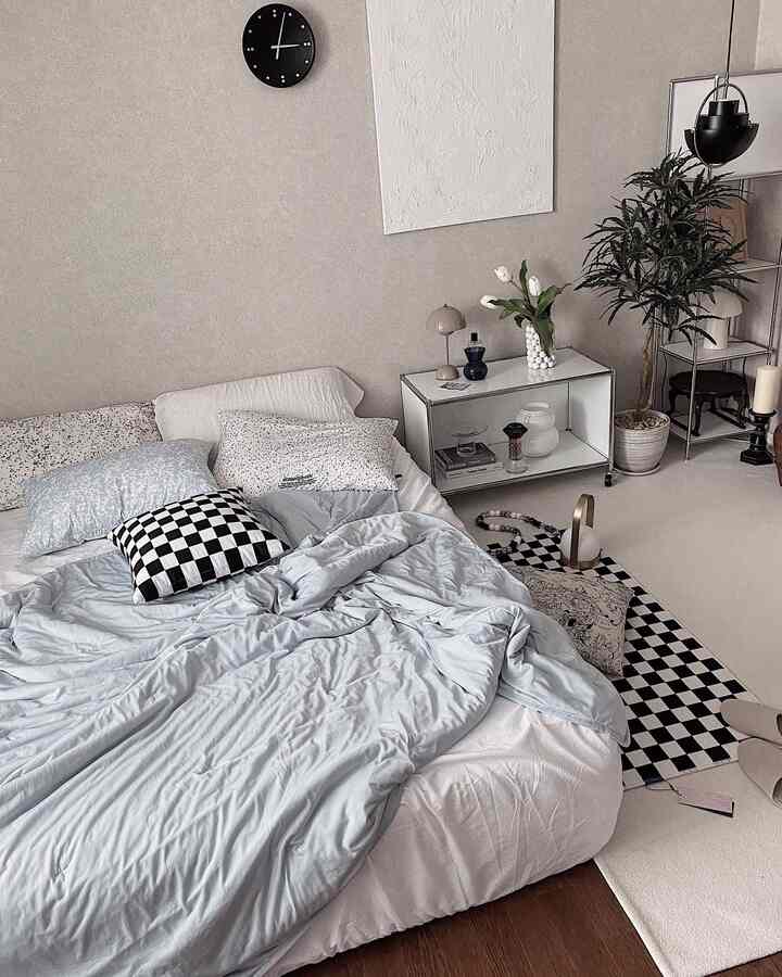 Beige and white toned bedroom featuring blue bedding and cushions with a checkered rug in a minimal Japandi style space