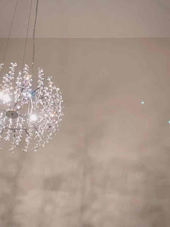 Elegant lighting space featuring a silver chandelier against beige walls with a soft ambient tone