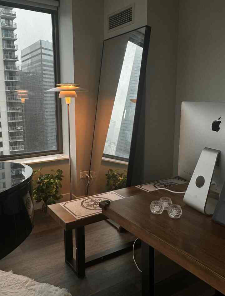 Wood tone home office with natural light, featuring large standing mirror and floor lamp in a modern setting