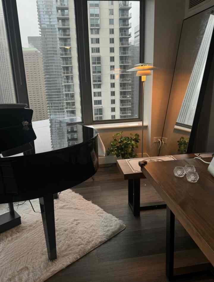 Modern natural living room with white walls, wooden furniture, large windows, and a grand piano