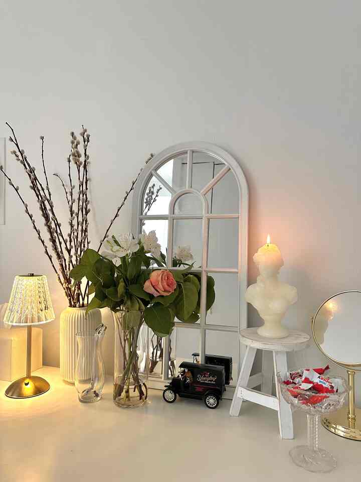 White-toned entrance area featuring vases, candle on stool, and mirror in a French Country style setting