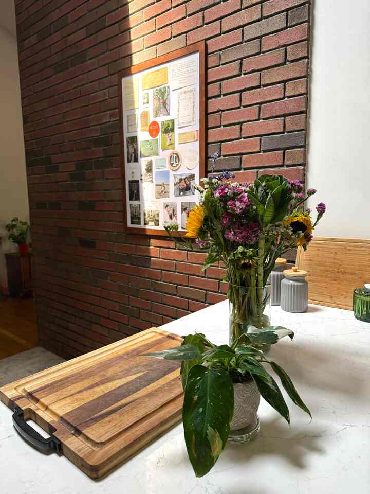 Warm brown-toned kitchen space featuring wooden cutting boards, a vase of flowers and potted plant with cozy atmosphere