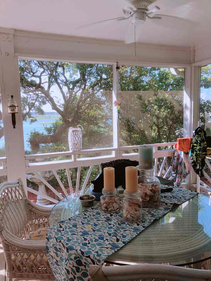 White and blue toned veranda featuring a glass table with candles and a pet cat, creating a natural atmosphere