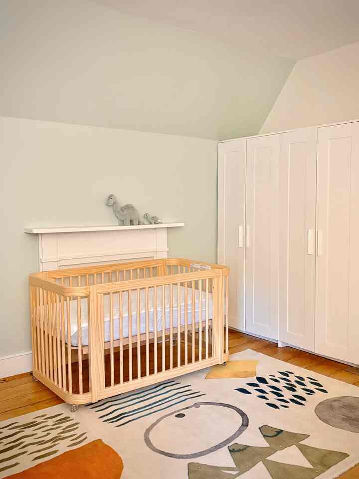Natural color and white toned kids' room featuring a wooden baby crib and white wardrobe, creating a peaceful atmosphere