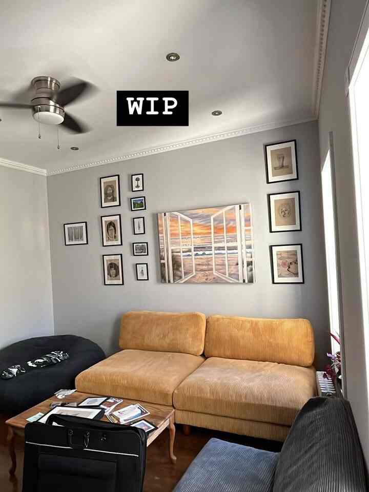 White and yellow toned living room featuring a yellow corner sofa, black bean bag, and various framed wall art in a cozy space