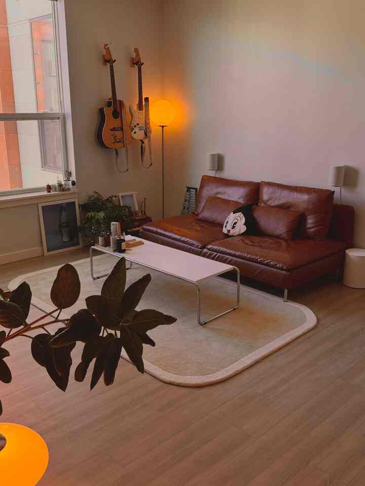 Natural brown and beige toned living room featuring a brown leather sofa and white coffee table with cozy atmosphere
