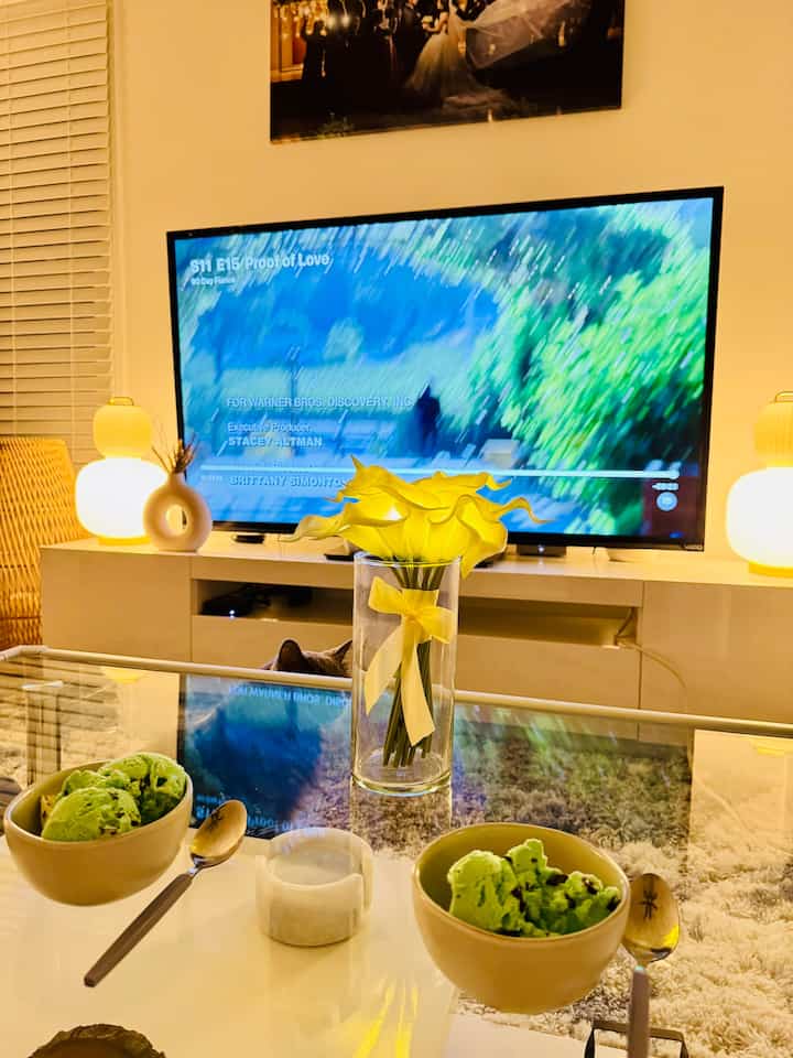 White and yellow toned living room featuring glass coffee table with yellow vase and lamps creating a cozy atmosphere
