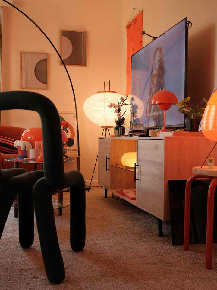 Warm orange and natural toned living room featuring minimalist TV stand and floor lamp in a simple setting