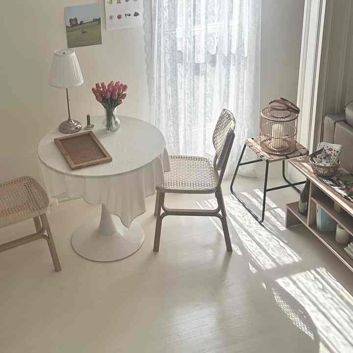 White and beige toned dining room featuring rattan chairs and round table with cozy, calm home cafe atmosphere