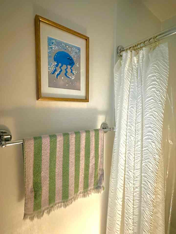 White and green toned bathroom featuring gold accents and a framed jellyfish painting with a fresh atmosphere