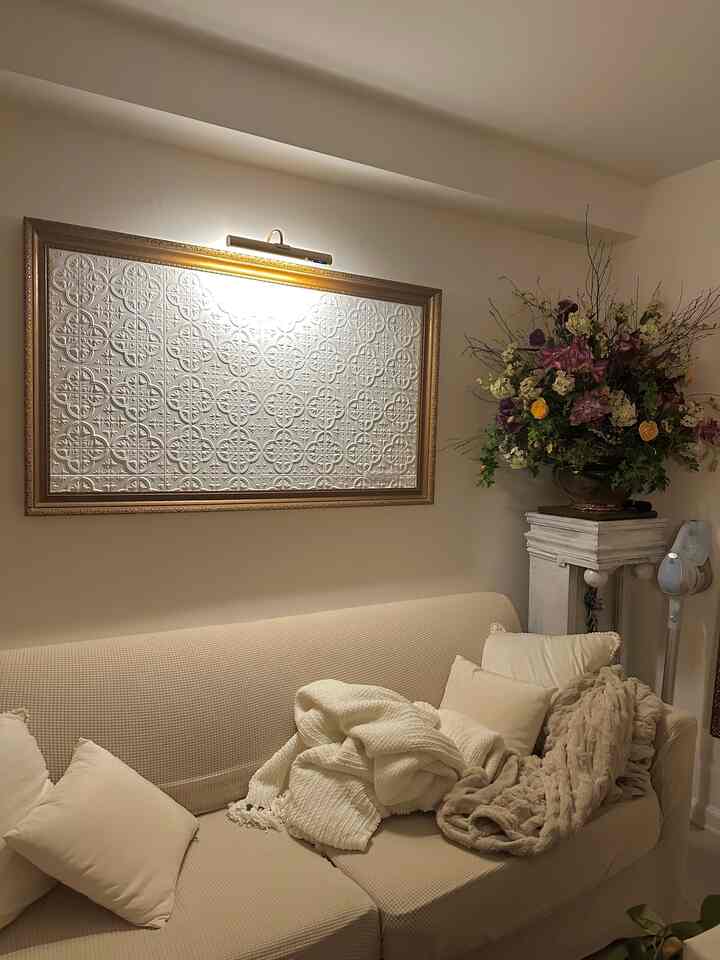 Beige-toned living room featuring carved wall art in gold frame above a beige sofa with white cushions and throws creating a cozy atmosphere