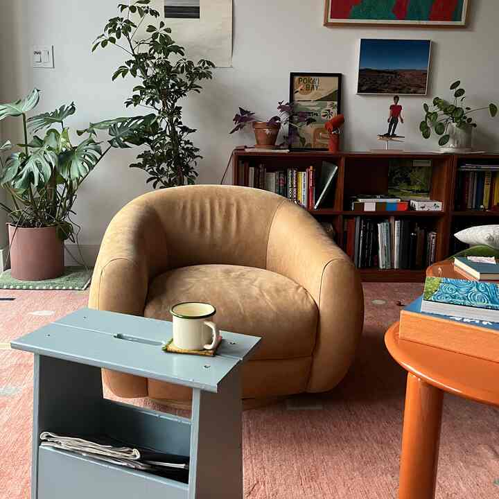 Natural style living room featuring a beige sofa, orange coffee table, and multiple plants