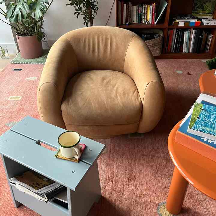 Retro styled living room featuring a warm caramel brown armchair and pastel blue DIY storage side table