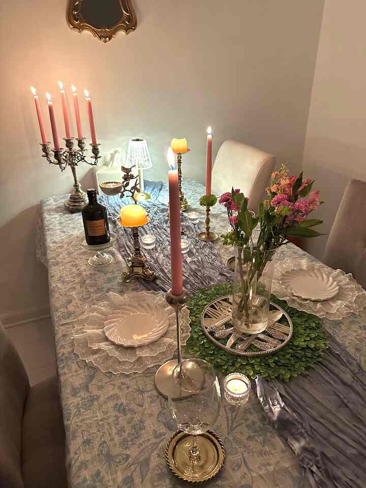 Pink and white toned dining room featuring a table with lit candles and flowers, creating a cozy atmosphere
